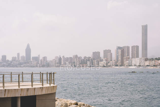 Skyline of Benidorm city with contemporary architecture seen from the waterfront of sea with pier — стоковое фото