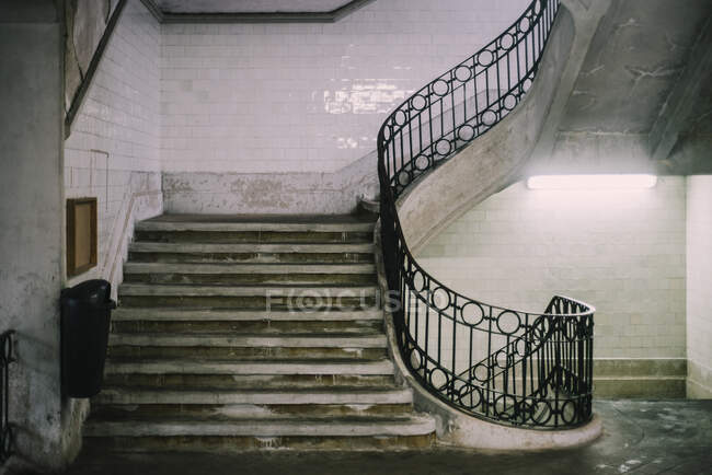 Innenraum eines schäbigen Hauses, Steintreppe mit Metallgeländer und gefliesten Wänden — Stockfoto