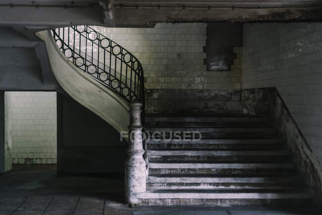 Interior of shabby house, stone stairway with metal railing and tiled walls — Stock Photo