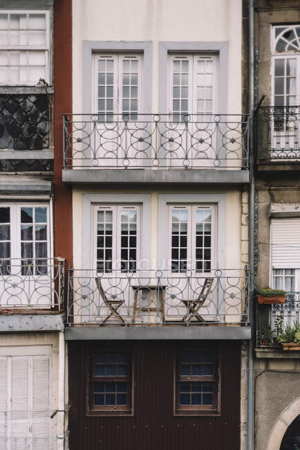 Esterno di casa invecchiata con pareti intemperie e balconi con ringhiere metalliche — Foto stock