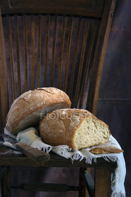 Mocassini di pane saporito e coltello appoggiati su un pezzo di stoffa su una sedia di legno — Foto stock