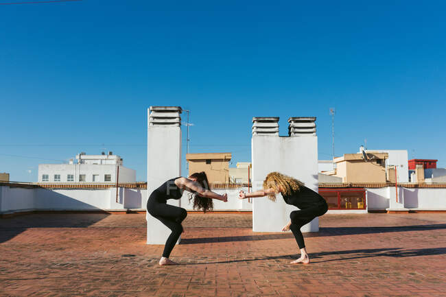Mujeres practicando yoga juntas en la azotea - foto de stock