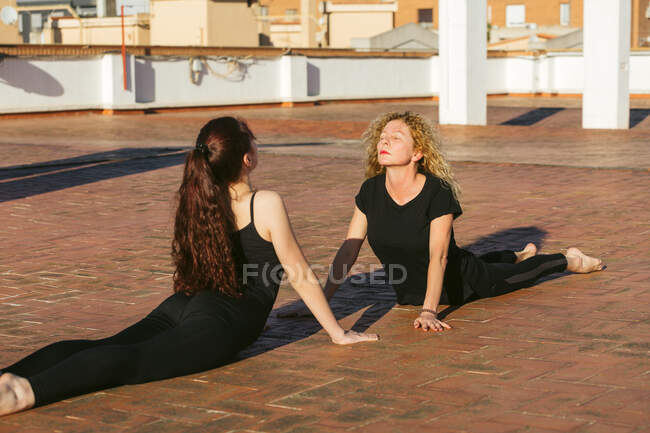 Mulheres flexíveis praticando ioga volta dobrar asana no terraço — Fotografia de Stock