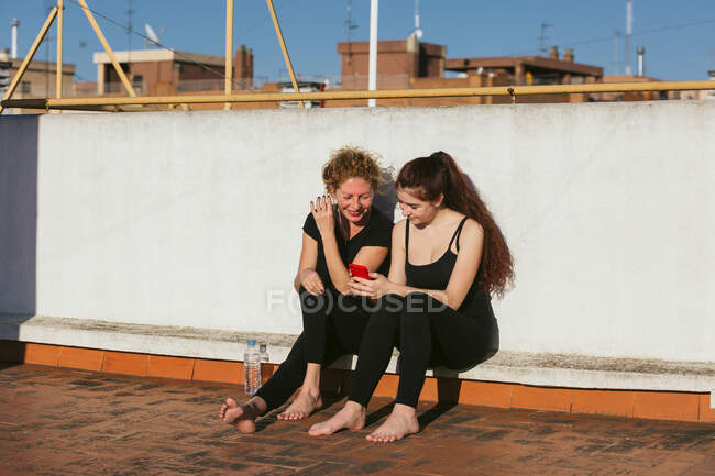 Mulheres com smartphone descansando após a prática de ioga — Fotografia de Stock