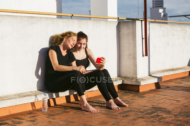 Женщины со смартфоном отдыхают после занятий йогой — стоковое фото