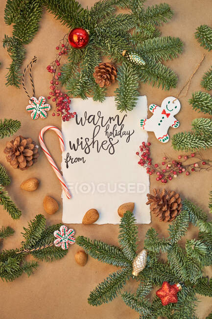 Tibios deseos de vacaciones letras en la tarjeta rodeada de decoraciones de Navidad - foto de stock
