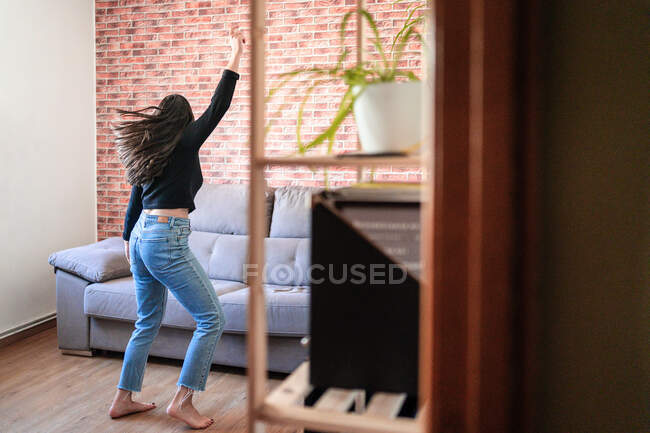 Анонімна жінка танцює вдома. Вона повернулася. За нею цегляна стіна — стокове фото