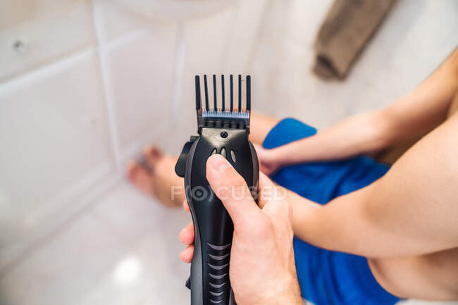 From above of guy with hair trimmer standing in modern bathroom near crop male friend — Stock Photo