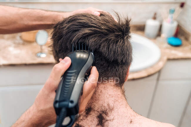 Männchen mit Haarschneider schneiden Haare von Kerl in zeitgenössischem Badezimmer zu Hause — Stockfoto