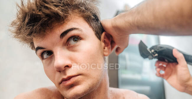 Чоловік з тримером для стрижки волосся хлопця у сучасній ванній вдома — стокове фото