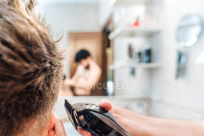 Чоловік з волоссям, що підстригає волосся хлопця в сучасній ванній кімнаті. — стокове фото