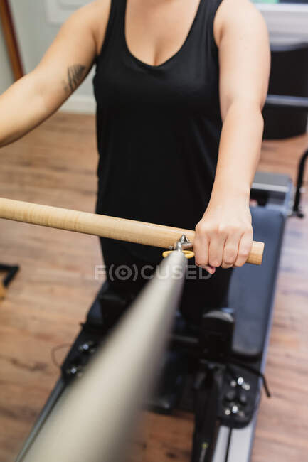 Unrecognizable male athlete exercising with wooden horizontal bar of pilates reformer in contemporary gym — Stock Photo
