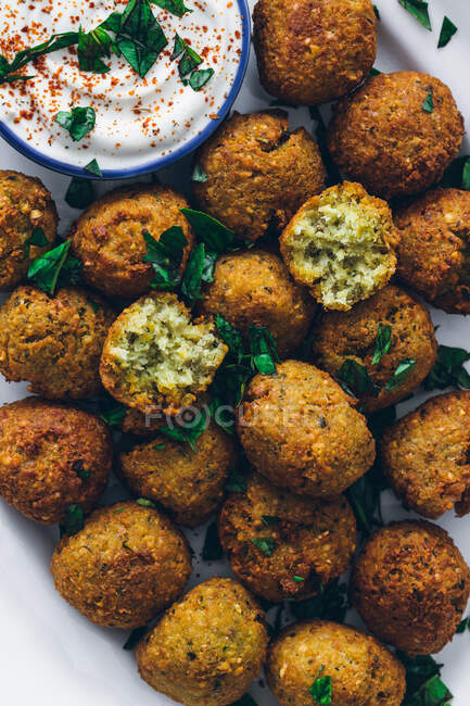 Top view of fried falafel made of legumes served with sour cream sauce on plate — Stock Photo