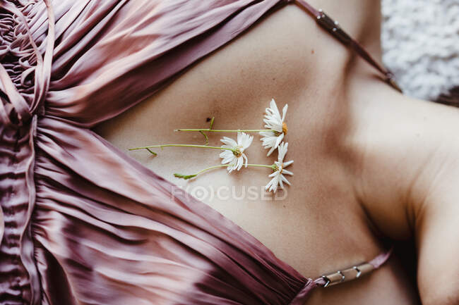 Plan recadré de poitrine féminine avec des détails de robe de soie et des fleurs de camomille — Photo de stock