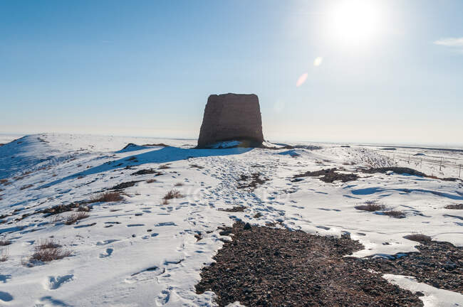 Stone on snowy hilltop in bright sunlight under blue sky — Stock Photo