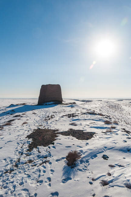 Piedra en la colina nevada en la luz del sol brillante bajo el cielo azul - foto de stock
