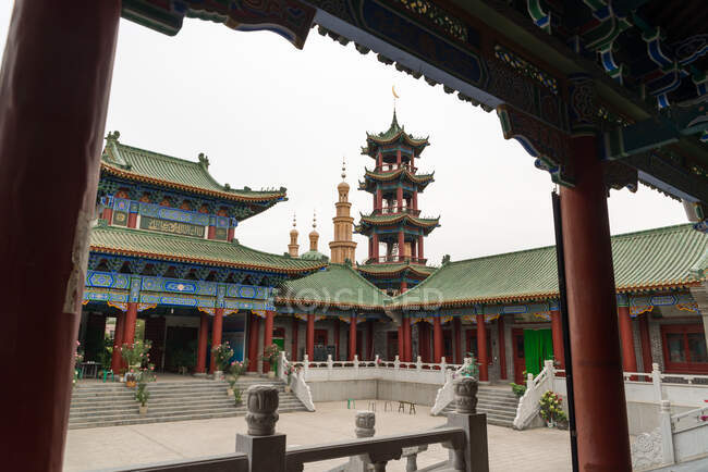 Exterior do edifício oriental com telhado curvo e pagodes ornamentais com mesquita muçulmana no fundo — Fotografia de Stock