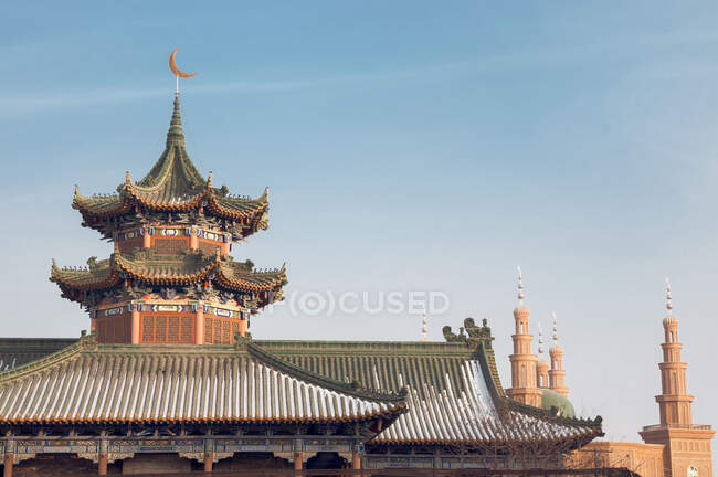 Exterior of oriental building with curved roofs and ornamental pagodas on blue sky background — Stock Photo
