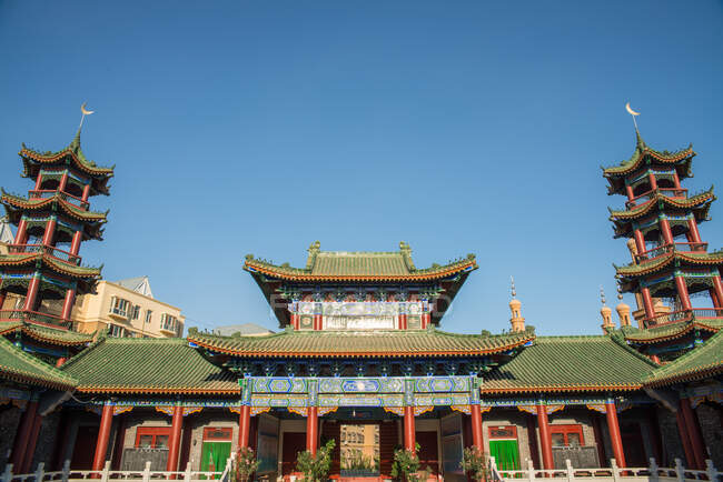 Low angle of exterior of oriental building with curved roofs on background of cloudless sky — Stock Photo