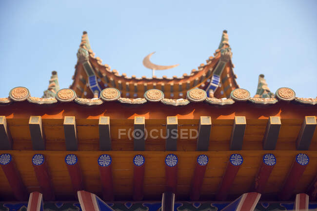 Low angle view of wooden curved roof of traditional building on background of blue sky — Stock Photo