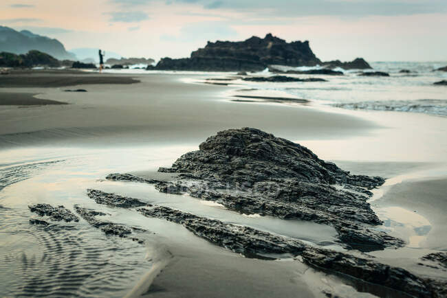 Costa arenosa húmeda con formaciones rocosas ásperas, Taiwán - foto de stock