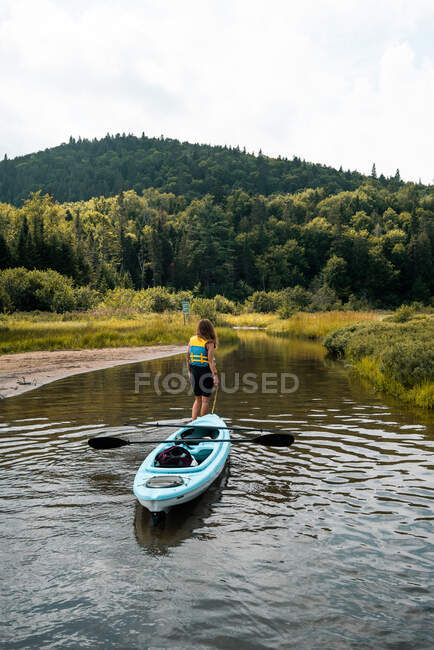 Back view of unrecognizable female traveler with kayak standing in clean water of river and admiring green hill in La Mauricie National Park in Quebec, Canada — Stock Photo