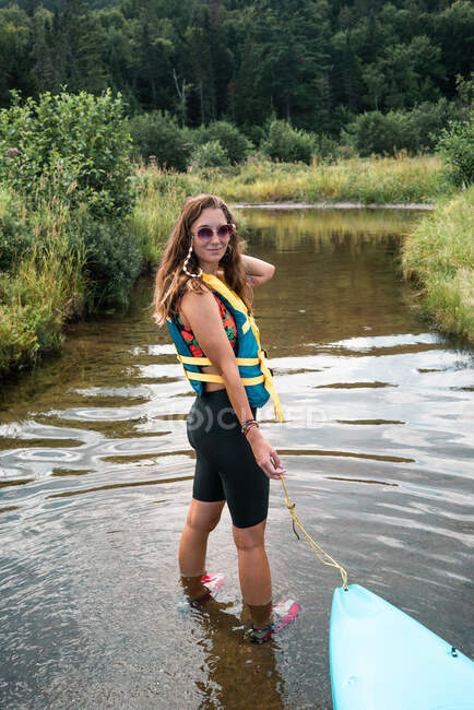 Жіночий мандрівник з каяком стоїть у чистій воді річки і милується зеленим пагорбом у Національному парку Ла - Маурічі (Квебек, Канада). — стокове фото