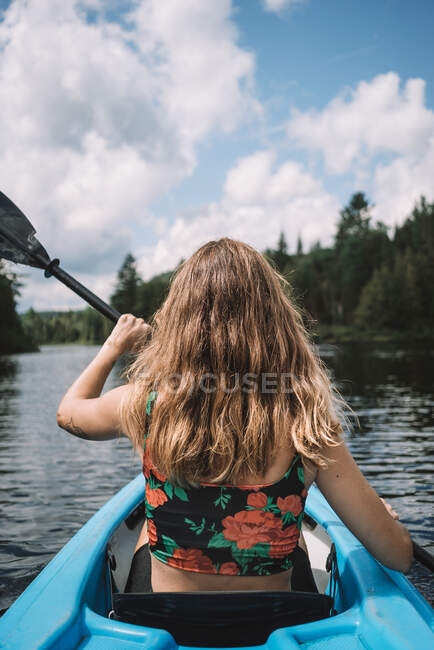 Rückansicht einer anonymen Reisenden in Schwimmweste, die im Boot sitzt, während einer Flussfahrt vor bewölktem Himmel im La Mauricie Nationalpark in Quebec, Kanada — Stockfoto