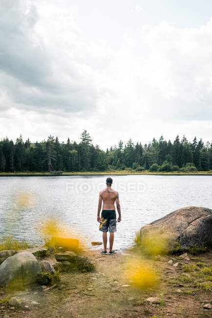 Back view of traveler standing on shore of calm rive on cloudy day in La Mauricie National Park in Quebec, Canada — Stock Photo