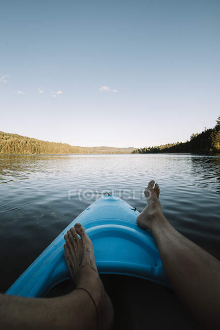 Recorte explorador descalzo relajarse en barco durante el viaje por el río en el Parque Nacional La Mauricie en Quebec, Canadá - foto de stock