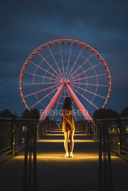 Anonymous female tourist on illuminated pier with glowing on background Ferris wheel in Montreal — Stock Photo