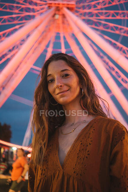 Young woman tourist standing on illuminated pier looking at camera with glowing on background Ferris wheel in Montreal — Stock Photo