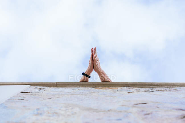 From below of unrecognizable crop person with black bracelet on hand clapping hands against blue cloudy sky on rooftop in city — Fotografia de Stock