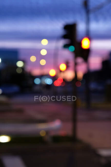 Luzes brilhantes desfocadas de semáforo localizado na encruzilhada da cidade durante o majestoso pôr do sol — Fotografia de Stock