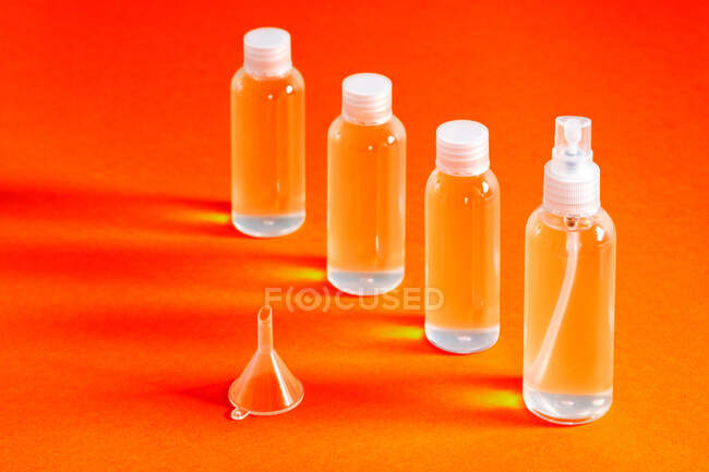 Vários frascos claros com gel clorídrico junto com um funil para encher serve para desinfetar as mãos — Fotografia de Stock
