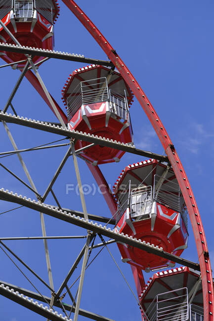 De dessous de la grande roue avec des cabines rouges situées sur le parc d'attractions par une journée ensoleillée avec ciel bleu — Photo de stock