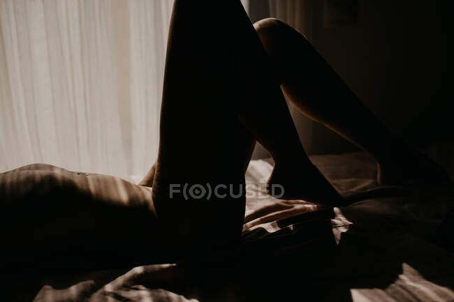Спокуслива жінка з голими грудьми лежить на зручному ліжку в інтимній атмосфері і має сексуальне задоволення під час карантину — стокове фото