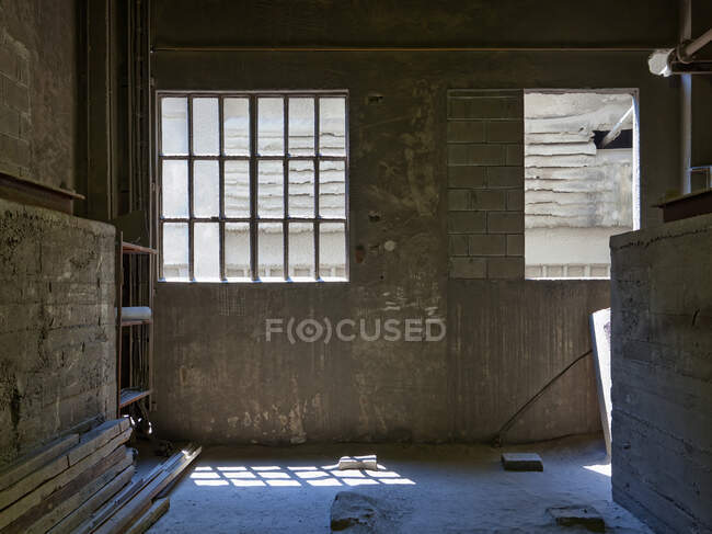Weathered concrete reconstruction room located on territory of desolate factory with timber inside against gray wall of worn out building — Foto stock