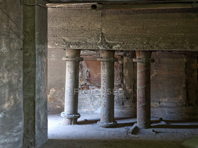 D'énormes tuyaux rouillés encastrés dans le sol en béton au milieu de la pièce dans la pièce abandonnée de vieux bâtiment minable — Photo de stock