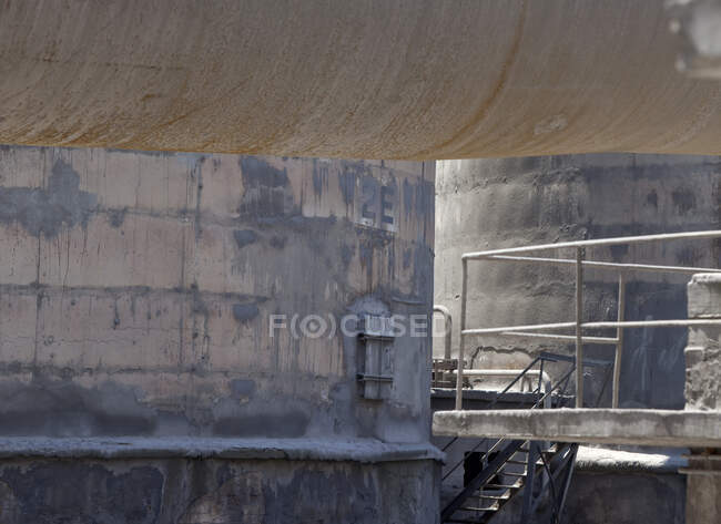 Металлические лестницы, соединяющие промышленное оборудование с гранжевым трубопроводом на территории металлургического завода в дневное время — стоковое фото