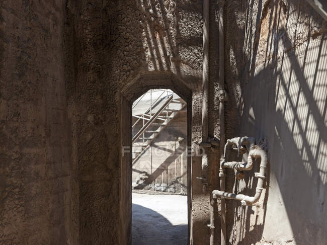 Промышленный коридор с узкой аркой напротив лестницы на расстоянии изношенного завода в дневное время с дневным светом сверху — стоковое фото