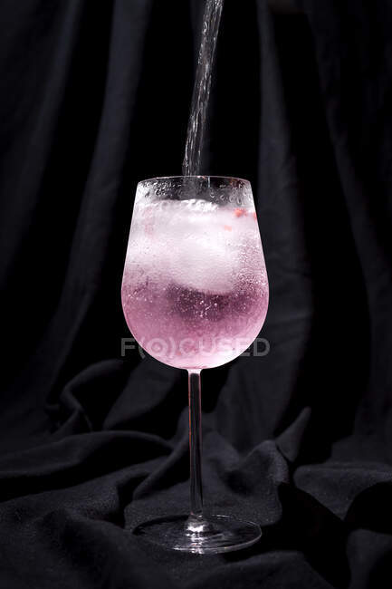 Gin tonic cocktail with pink tonic water, pink pepper, rosemary, mint,cinnamon,lemon and orange on dark background — Stock Photo