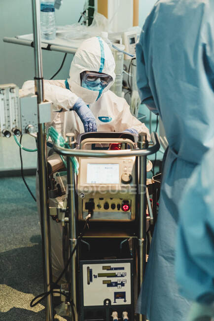 Médecin professionnel en uniforme de protection et gants vérifiant l'équipement avant d'effectuer l'opération dans la salle d'opération dans la clinique moderne — Photo de stock