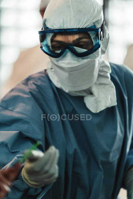 Professioneller Chirurg in Schutzuniform mit Handschuhen und Maske, der im Operationssaal eines modernen Krankenhauses operiert — Stockfoto