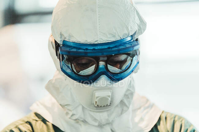 Médico profesional serio en uniforme protector y máscara de pie en el quirófano moderno - foto de stock