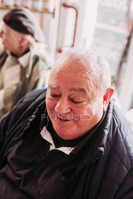 Пожилой счастливый мужчина проводит время с друзьями в уютном местном магазине деликатесов — стоковое фото