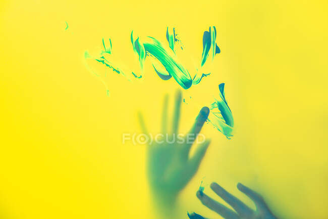 Artigiana del raccolto con le mani dipinte in piedi dietro parete gialla traslucida con pennellate — Foto stock