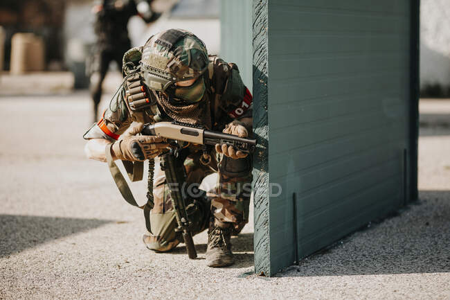 Airsoft player kneeling with shotgun — Stock Photo