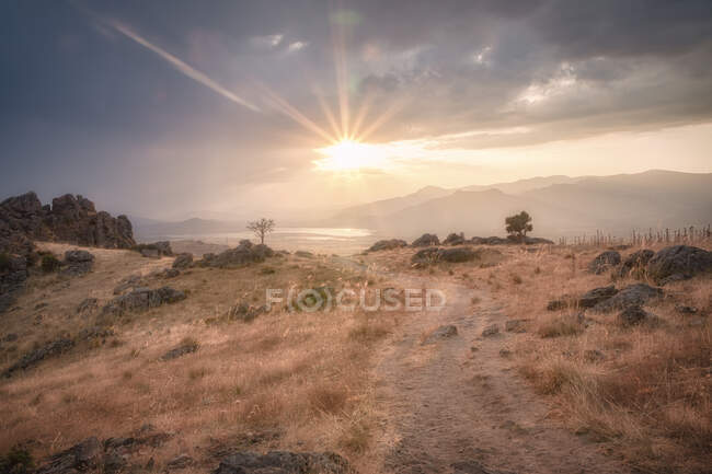 Strahlende Sonne am wolkenverhangenen Himmel über grasbewachsenen Hügeln am ruhigen Abend in Spanien — Stockfoto