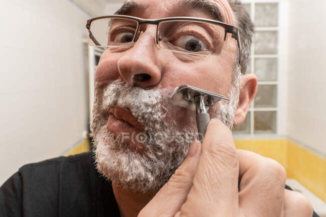 Бородатий чоловік голиться у ванній — стокове фото